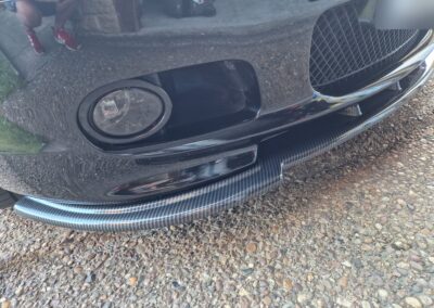 Carbon fibre front splitter beside the fog light on a BMW E46