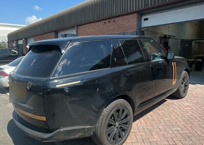 Black Range Rover with gold painted trims, rear three-quarter view